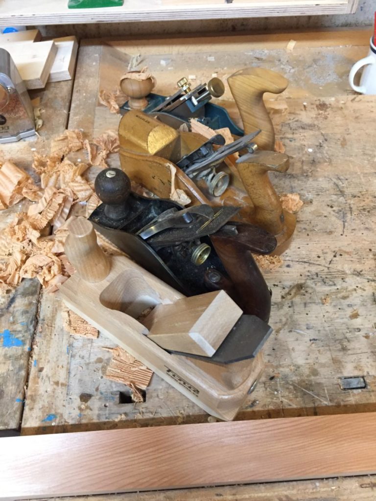 four woodworking planes on a bench